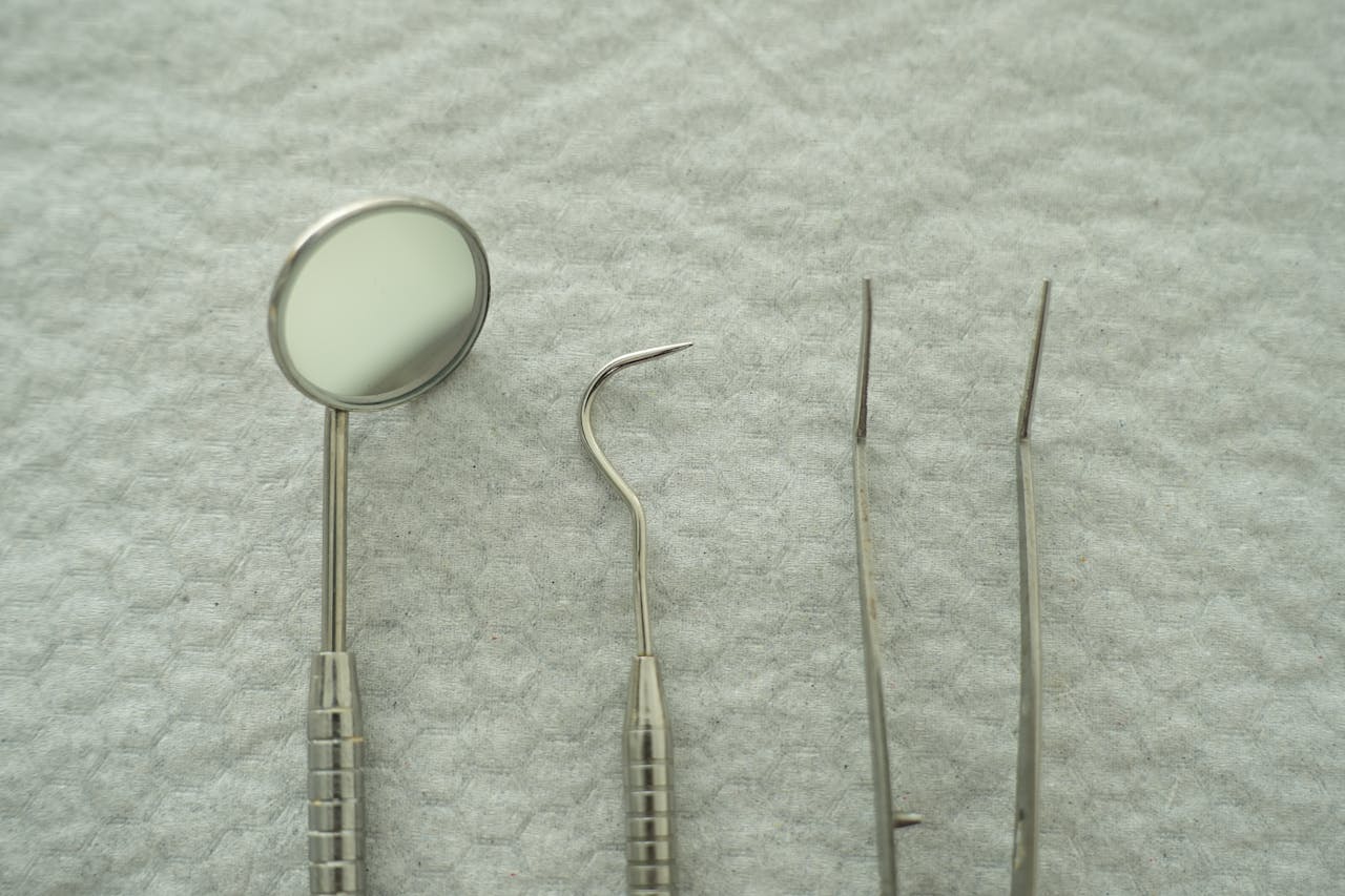Close-up of dental tools including mirror and pick on a gray textured background.